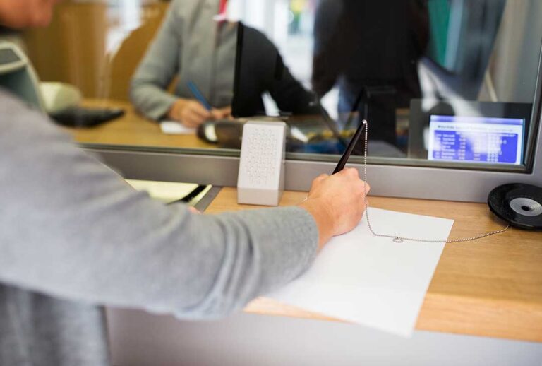Employee reviewing a retirement plan statement beside a calculator and laptop at a kitchen table.