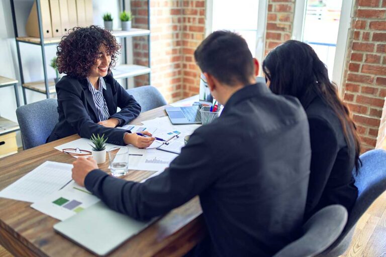A couple reviews retirement account statements and tax documents at a kitchen table.